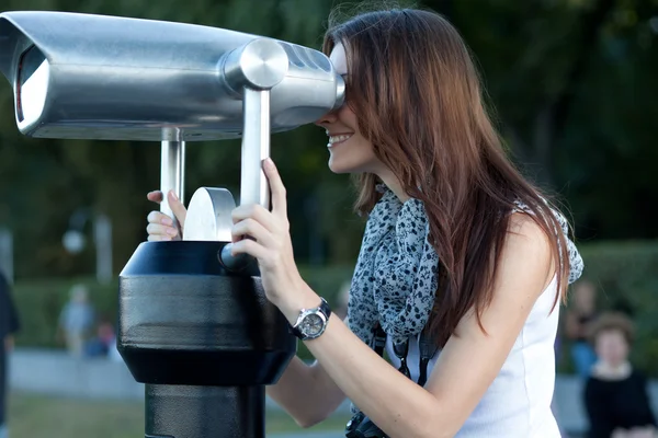 Mujer joven turista mira a través de un telescopio — Foto de Stock