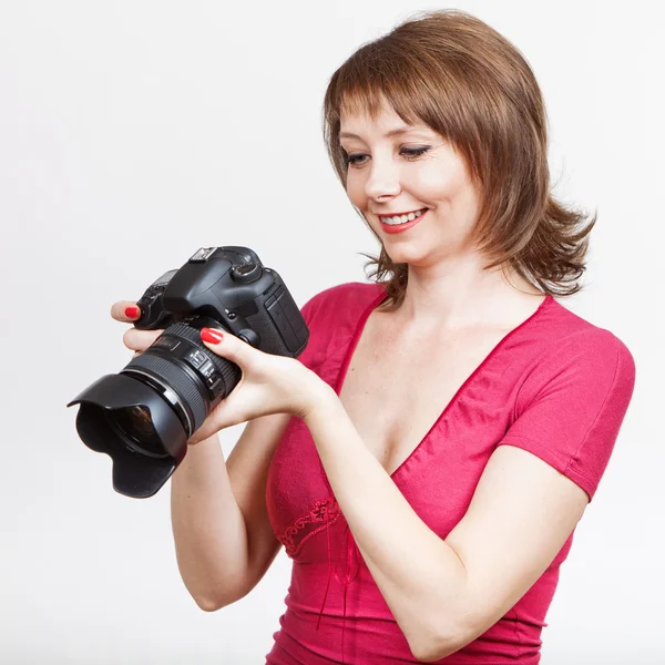 Mujer joven sosteniendo la cámara y mirando fotos — Foto de Stock