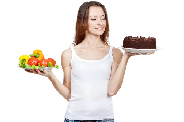 Making hard choice between vegetables and cake — Stock Photo, Image