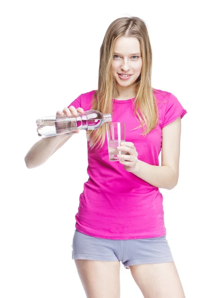 Giovane bella donna versa l'acqua in un bicchiere — Foto Stock