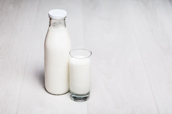 Botella de leche y vidrio sobre fondo de madera — Foto de Stock