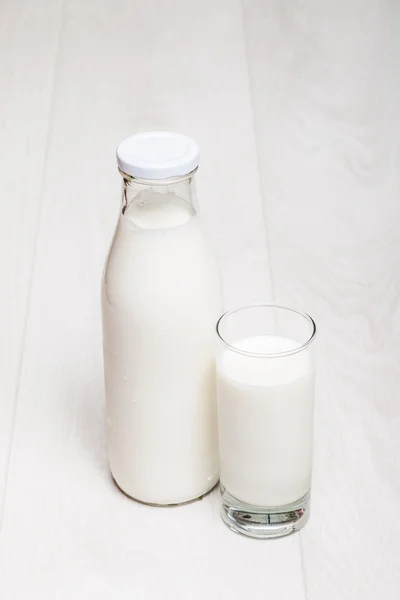 Botella de leche y vidrio sobre fondo de madera — Foto de Stock