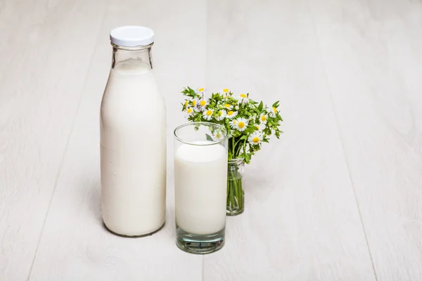 Milk bottle and glass on wooden background — Stock Photo, Image