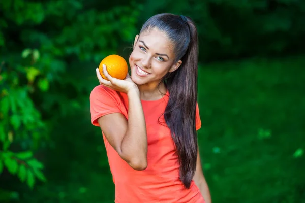 オレンジを保持している美しい若いブルネットの女性 — ストック写真