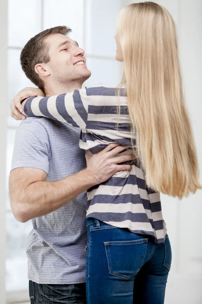 Glückliches junges kaukasisches Paar, das sich drinnen umarmt — Stockfoto