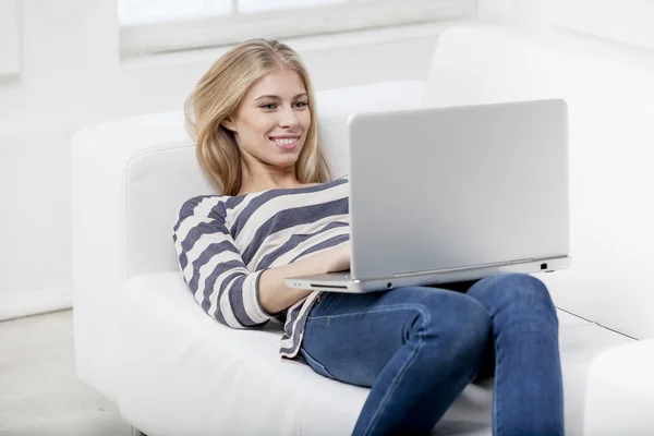 Donna sdraiata sul divano con laptop — Foto Stock