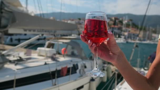 Egy nő, aki egy pohár bort tart a jachtok ellen Poros kikötőjében. Görögország — Stock videók