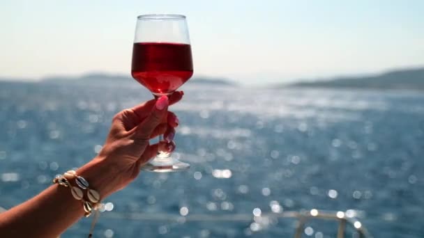 Ręka trzyma kieliszek wina na tle morza — Wideo stockowe