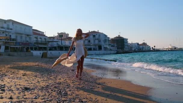 Vrouw met strohoed en witte jurk aan de kust bij Spetses, Griekenland — Stockvideo