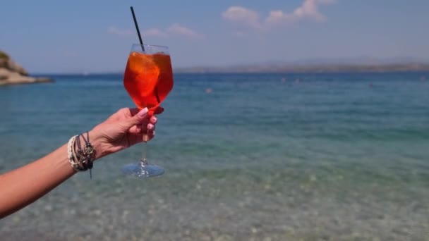 Weibliche Hand hält Glas Aperol Spritz Cocktail auf Meeresgrund — Stockvideo