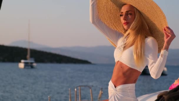 Gyönyörű nő visel szalmakalapot és fehér ruhát egy jachton élvezi az utazást, Spetses, Görögország, Európa — Stock videók