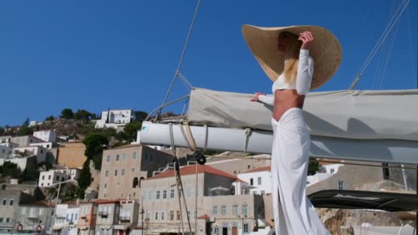 Kobieta w słomkowym kapeluszu i białej sukience relaksująca się na rejsie katamaranem żaglowca, Hydra, Grecja — Wideo stockowe