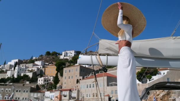 Mujer con sombrero de paja y vestido blanco relajante en un barco de vela catamarán de crucero, Hydra, Grecia — Vídeo de stock