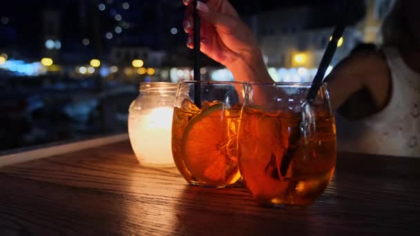 Vrouw die aperol Spritz cocktail drinkt zittend op zomerterras 's avonds in Hydra, Griekenland — Stockvideo
