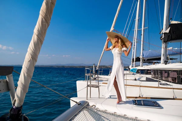 希腊，希腊，欧洲，一个戴着草帽，身穿白色长裙的漂亮女人在游艇上享受这段旅程 — 图库照片