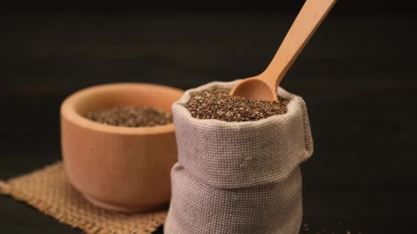 Сумка, повна органічного натурального насіння чіа на темному дерев'яному фоні або столі — стокове відео