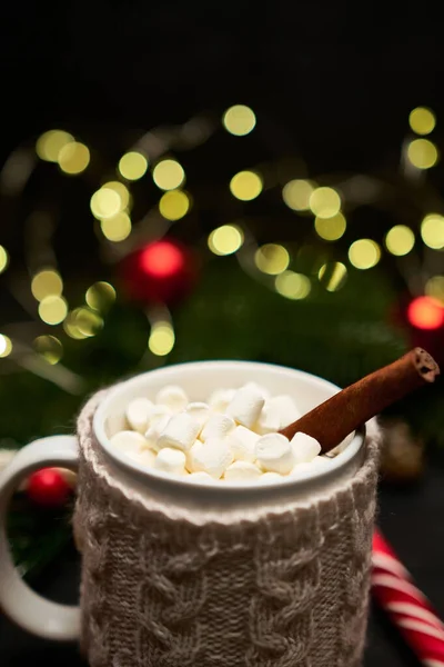 Horký kakaový nápoj se skořicovou tyčinkou a marshmallows s vánoční ozdobou na pozadí — Stock fotografie