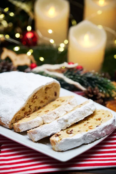 Sliced Traditional Christmas stollen cake with marzipan and New Year decorations on wooden background — Stock Photo, Image
