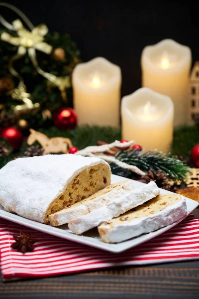 Sliced Traditional Christmas stollen cake with marzipan and New Year decorations on wooden background — Stock Photo, Image