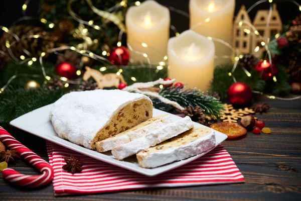 Sliced Traditional Christmas stollen cake with marzipan and New Year decorations on wooden background — Stock Photo, Image