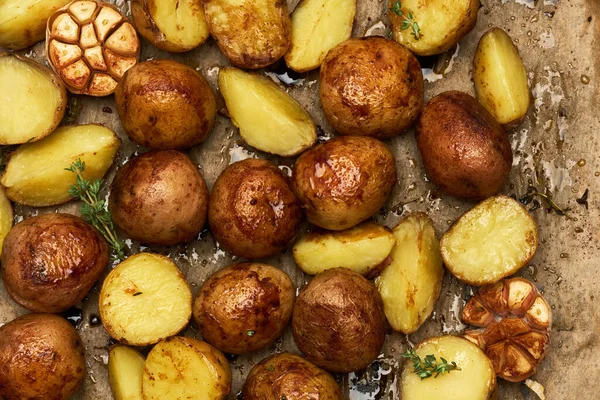 Пряный картофель в лотке с розмарином и чесноком на пергаментном слое — стоковое фото