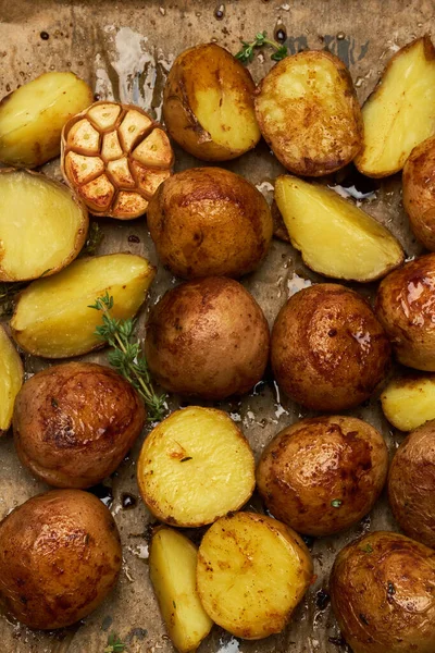 Пряный картофель в лотке с розмарином и чесноком на пергаментном слое — стоковое фото