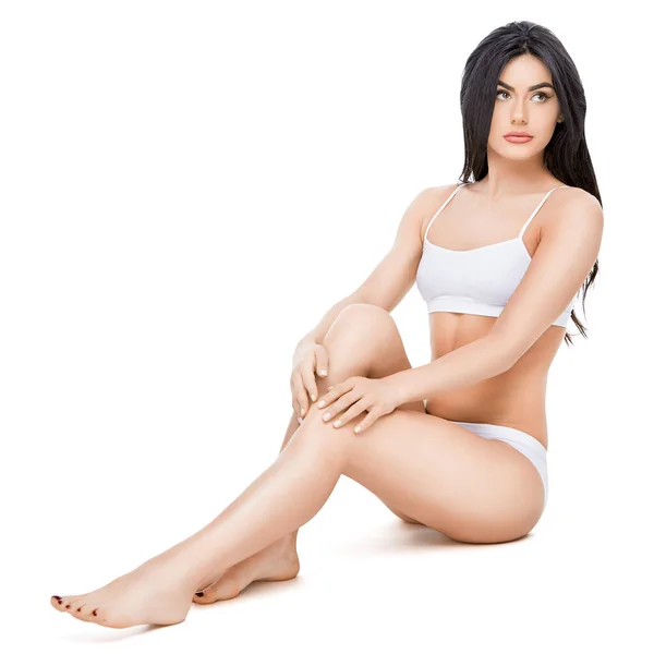 Fitness mladá žena s krásným tělem sedí na bílém pozadí — Stock fotografie