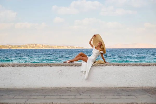 Toerisme concept - Jonge reizende vrouw geniet van het uitzicht op zee zittend aan de oude binnenstad dijk — Stockfoto