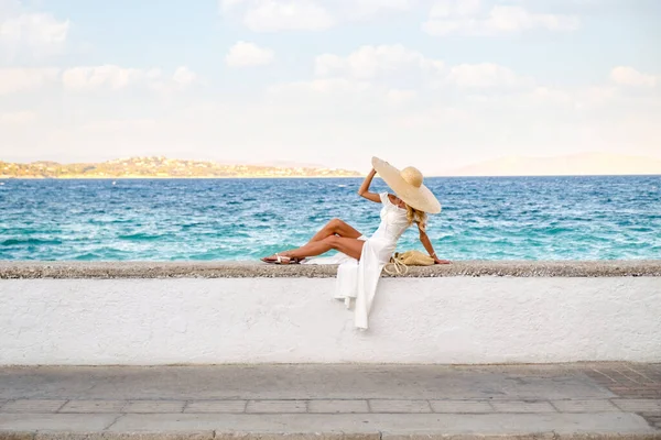 Toerisme concept - Jonge reizende vrouw geniet van het uitzicht op zee zittend aan de oude binnenstad dijk — Stockfoto