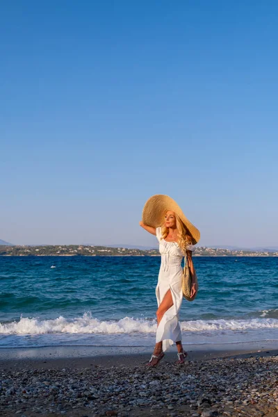 Aantrekkelijke jonge vrouw dragen jurk staan aan zee kust met handen opgeheven — Stockfoto