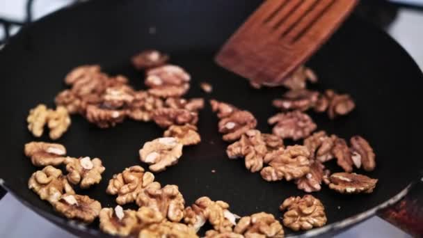 Primer plano de vídeo de nueces fritas en sartén hasta que estén doradas y mezcladas con espátula de cocina — Vídeo de stock