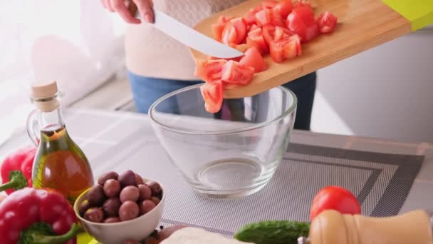 Grieks salade voorbereiding serie concept - vrouw gieten gesneden tomaten in een kom — Stockvideo