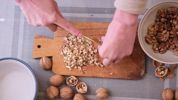Hakken van walnoten kernen met keukenmes op een hout snijplank — Stockvideo