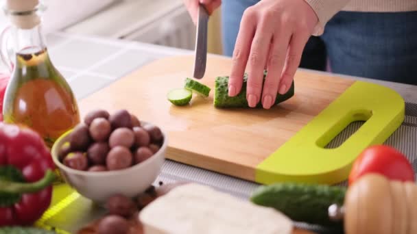 Grieks salade voorbereiding serie concept - vrouw snijden komkommers — Stockvideo