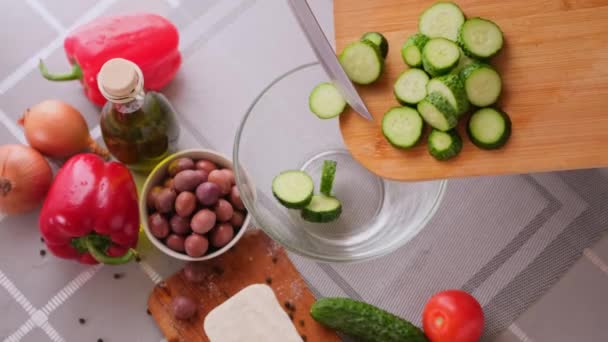 Koncept série přípravy řeckého salátu - žena nalévá nakrájené okurky do misky — Stock video