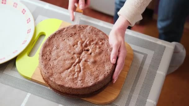 Frau schneidet Kruste von Karamell-Schokoladenkuchen auf Holzschneidebrett — Stockvideo