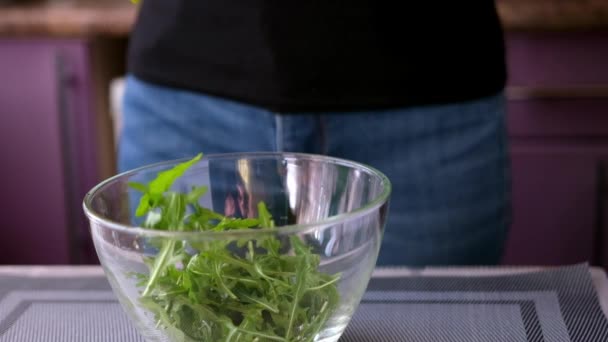 Healthy lifestyle - Woman pouring arugula into glass bowl — Vídeos de Stock