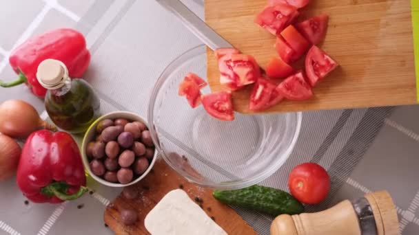 Koncepce série přípravy řeckého salátu - žena nalévá nakrájená rajčata do misky — Stock video