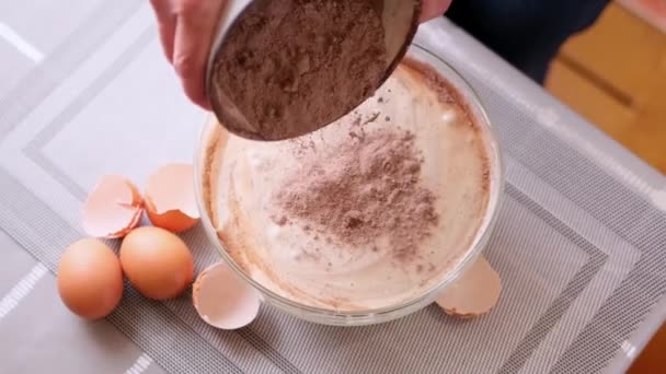Adding flour and cocoa to beaten eggs - making dough for baking — Vídeo de stock