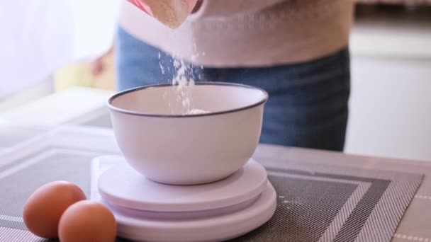Подготовка теста - Женщина-повар наливает муку в керамическую миску на кухонные весы — стоковое видео
