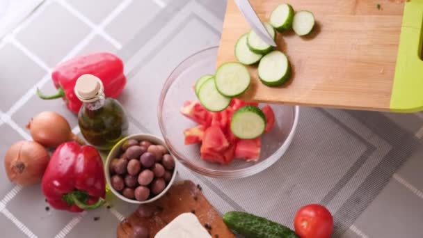 Koncept série přípravy řeckého salátu - žena nalévá nakrájené okurky do misky — Stock video