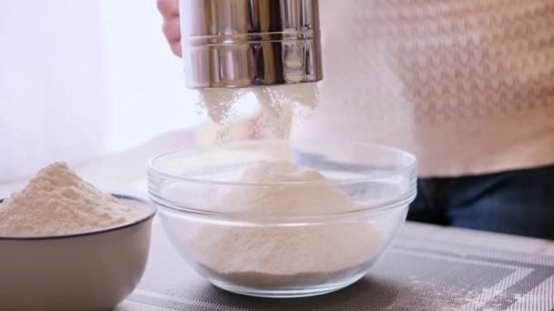 Close-up do conceito de padaria - Mulher peneirar farinha através de peneira metálica para tigela de vidro para assar — Vídeo de Stock