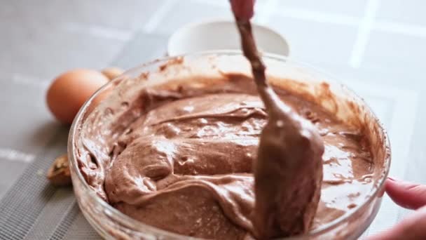 Fazer bolo de chocolate de noz - adicionar nozes à massa crua em uma tigela de vidro — Vídeo de Stock
