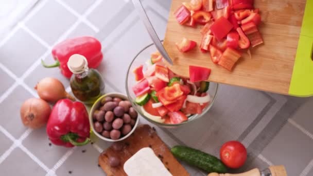 Concepto de la serie de preparación de ensalada griega - mujer vertiendo pimiento rojo en rodajas en un tazón — Vídeo de stock