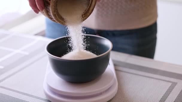 Dough preparation - Woman Cook pours sugar to ceramic bowl on kitchen scales — Stockvideo