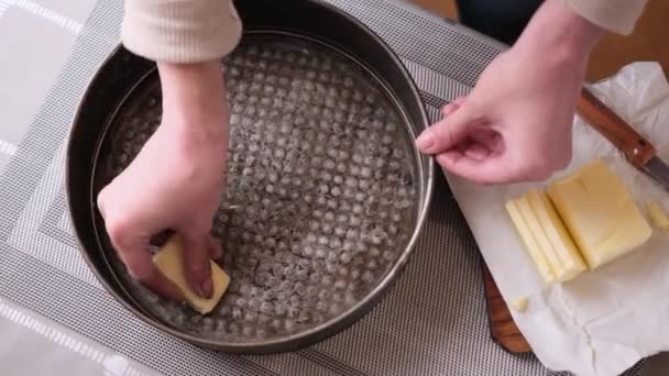 Nahaufnahme-Video von Frau, die eine Kuchenform zum Kuchenbacken buttert — Stockvideo