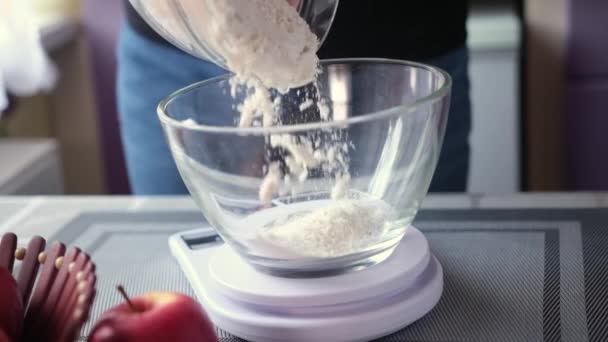 Apple pie preparation series - pouring flour into glass bowl standing on kitchen scales — стоковое видео