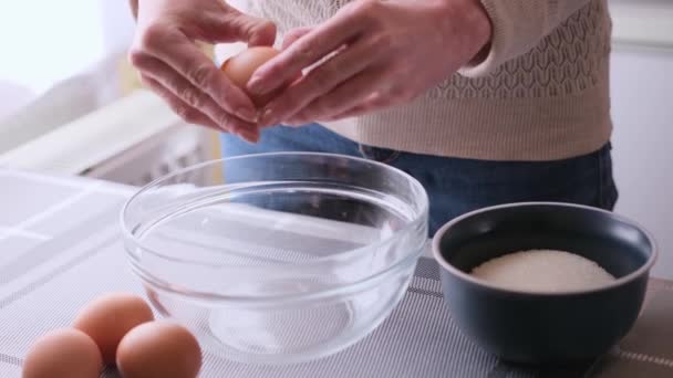 Žena drtí vejce do skleněné mísy a dělá těsto — Stock video