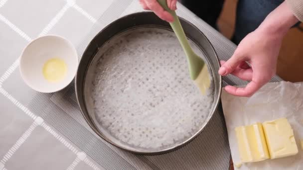 Видео крупным планом, где женщина намазывает масло на кастрюлю для выпечки торта — стоковое видео