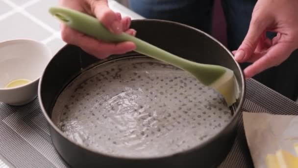 Видео крупным планом, где женщина намазывает масло на кастрюлю для выпечки торта — стоковое видео
